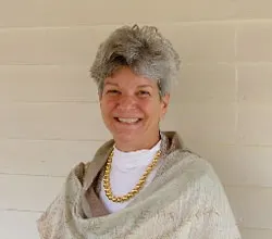 Anne Peyton, smiling, wearing a shawl and gold necklace.