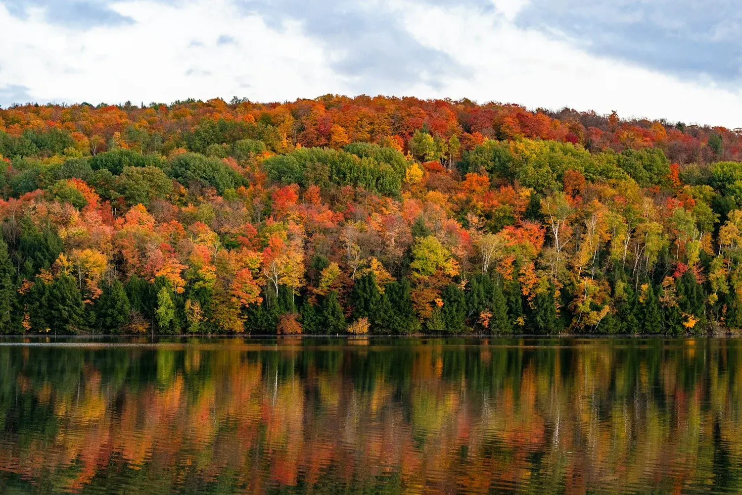 Autumn foliage reflected in a still Vermont lake, soft late-day light.